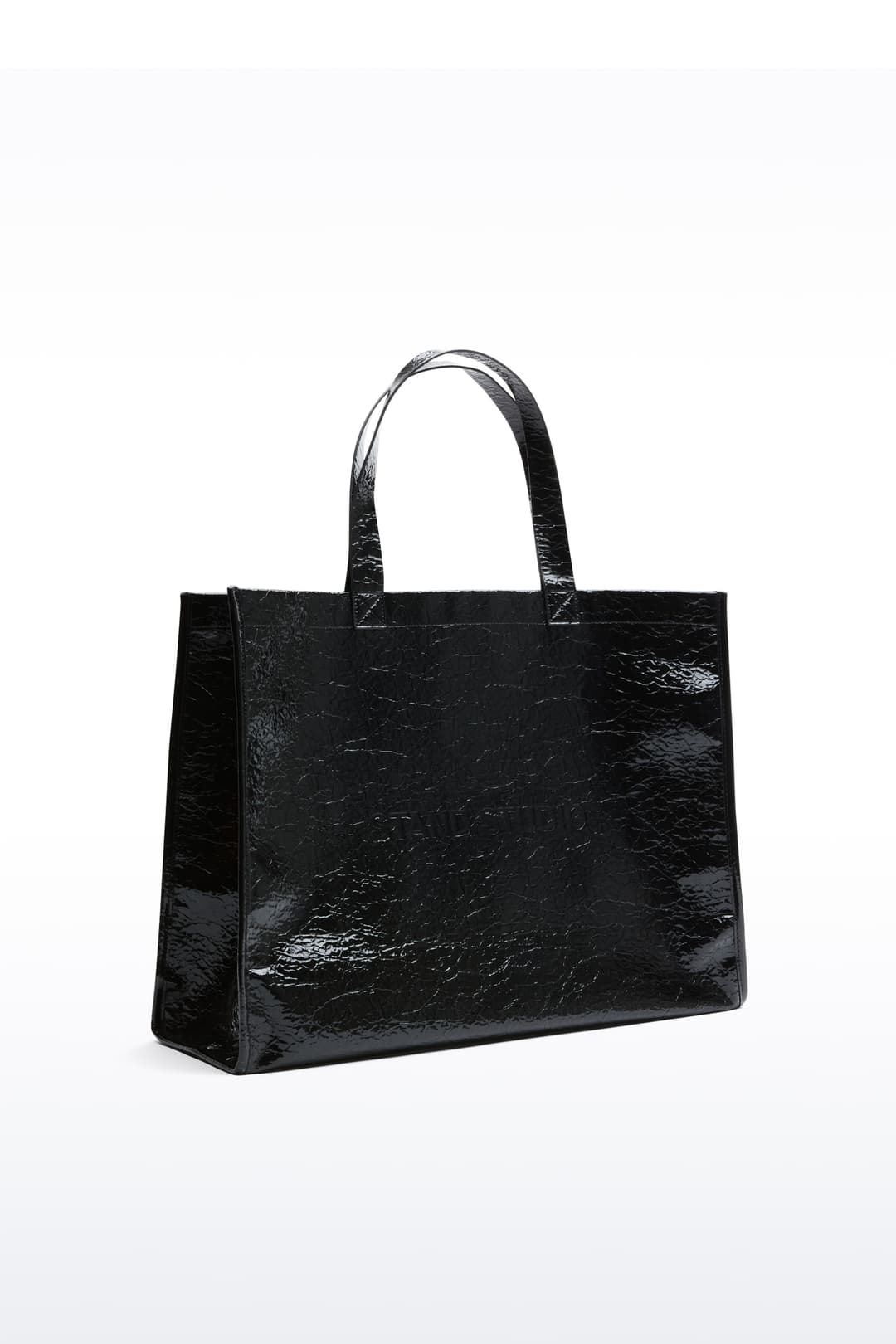 Side view of the Tiana Shopper in Black, is a classic tote bag crafted in bonded faux leather with a textured finish.