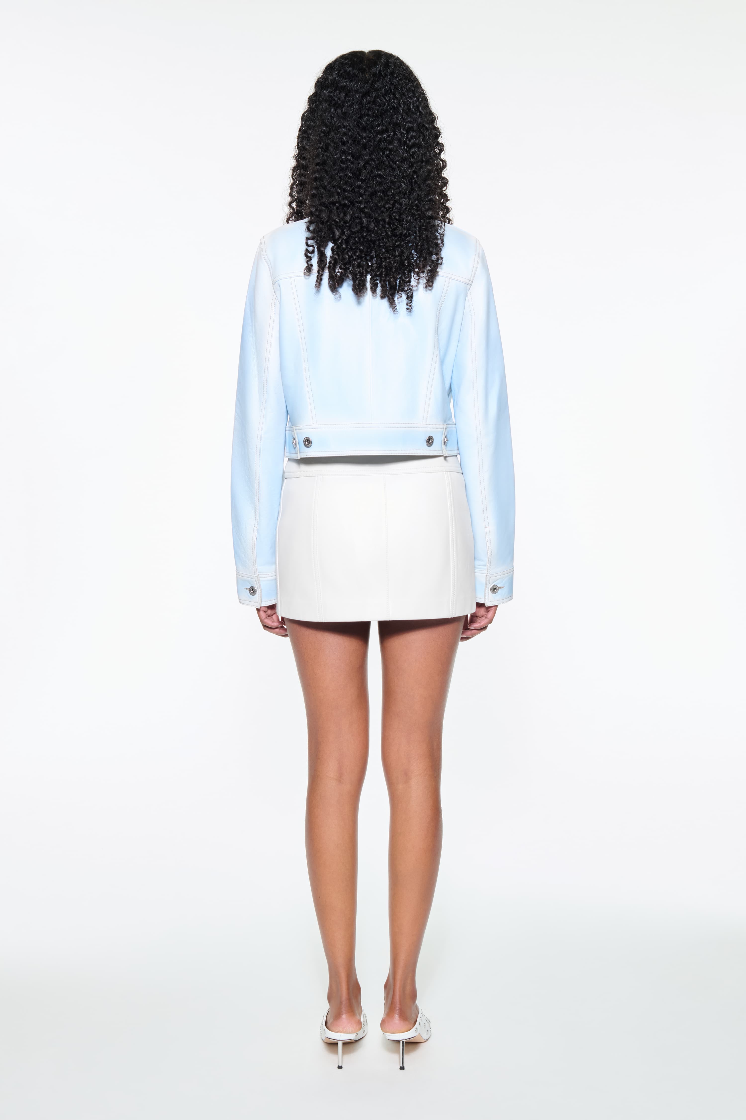 Back view of the Calliope Jacket in Blue Lagoon, is crafted in supple lamb leather and features a cropped silhouette. The color is a soft light blue.