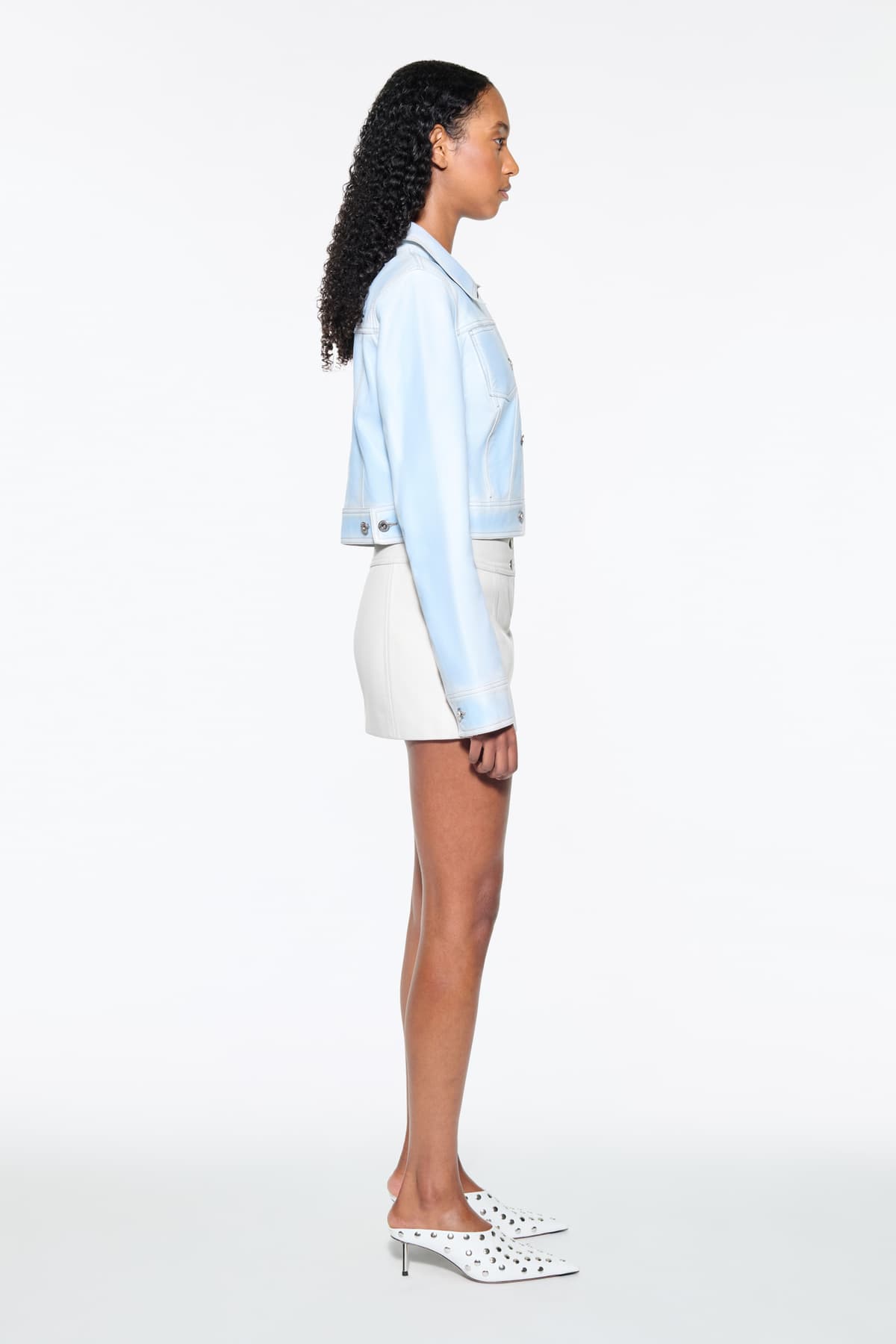 Side view of the Calliope Jacket in Blue Lagoon, is crafted in supple lamb leather and features a cropped silhouette. The color is a soft light blue.