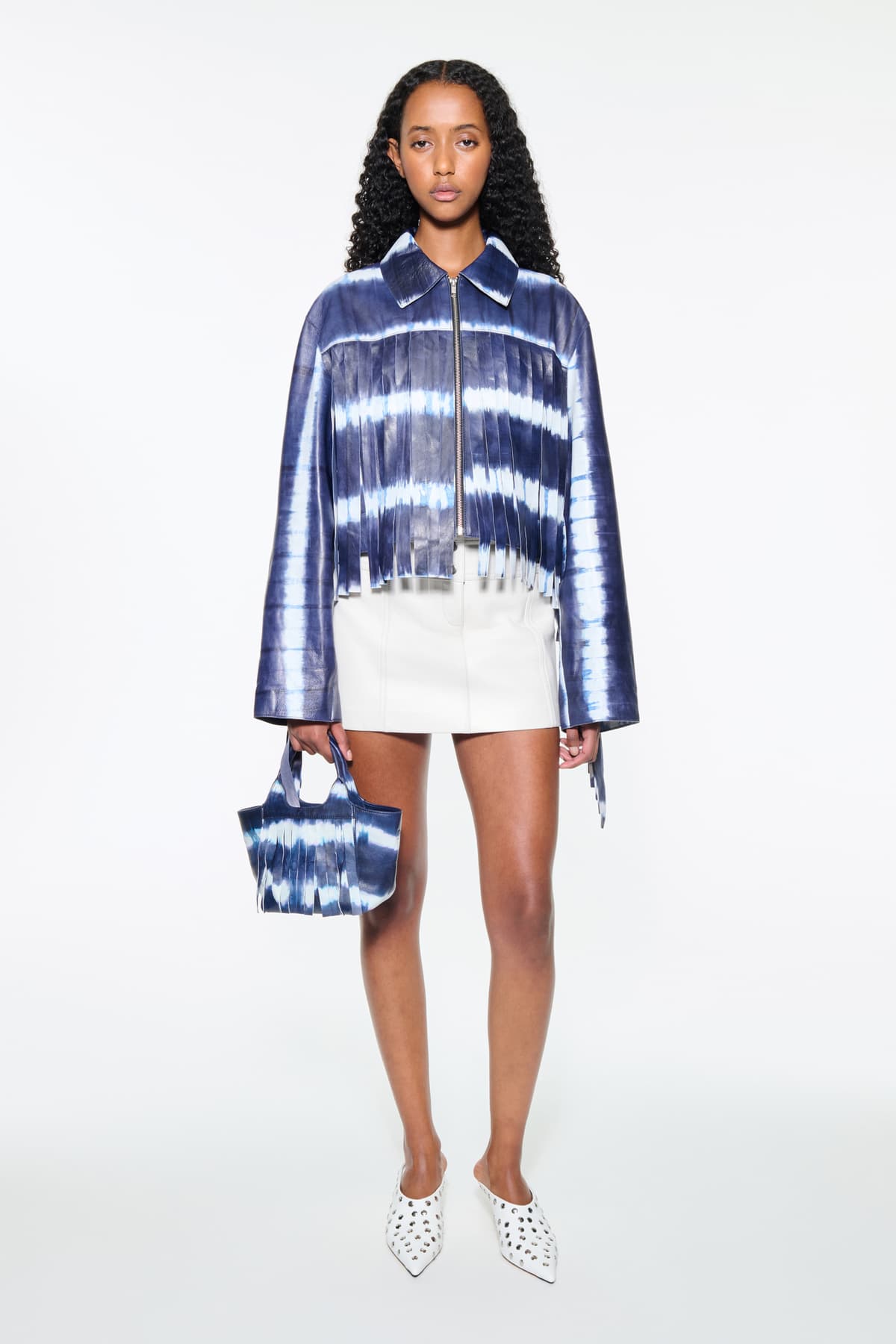 Front view of the Charlotta Fringe Jacket in Ocean Tie Dye, is designed in leather with a cropped silhouette and raw edge finishes. The color is a dark blue with white tie-dye pattern.