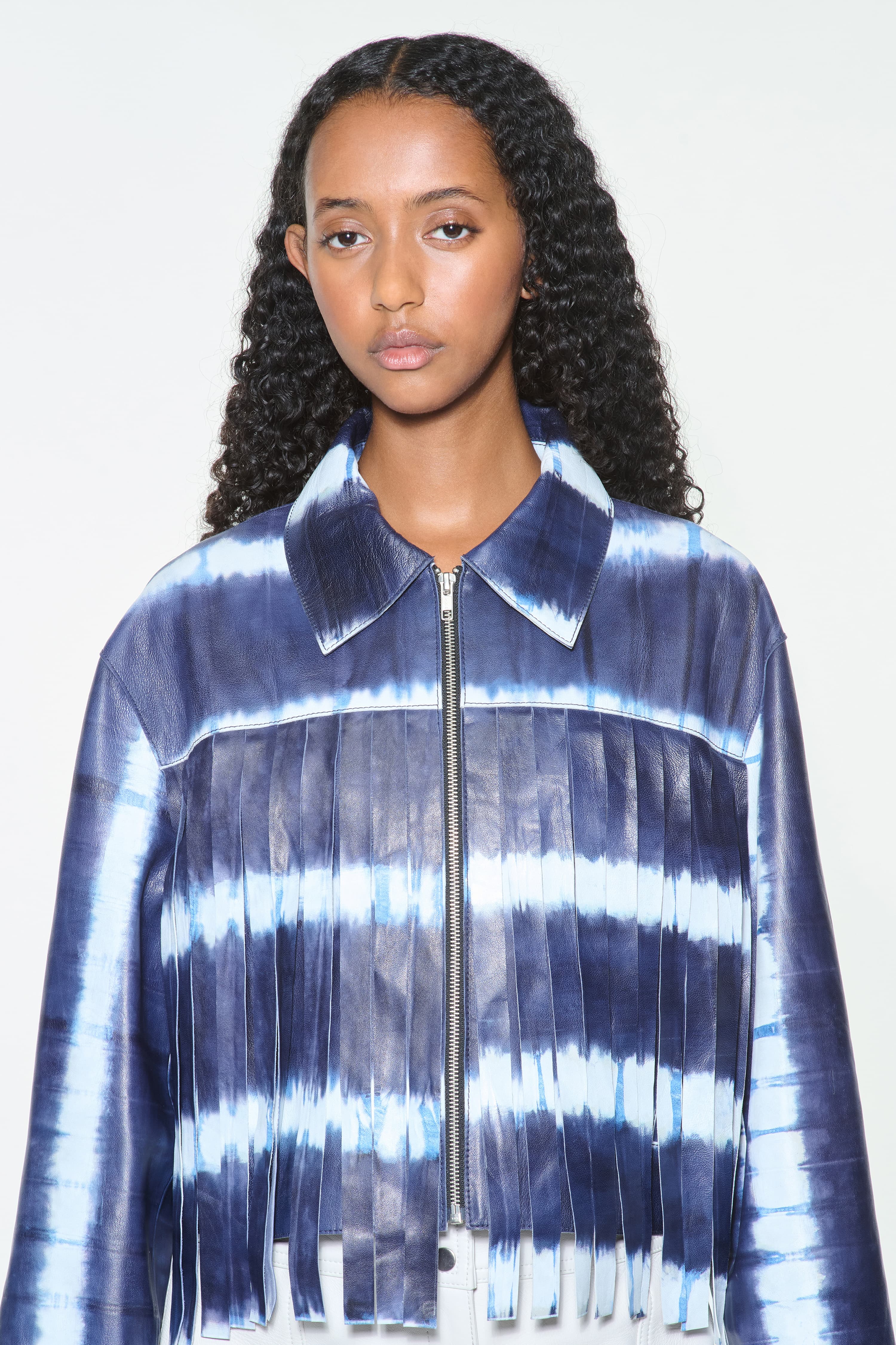 Close-up view of the Charlotta Fringe Jacket in Ocean Tie Dye, is designed in leather with a cropped silhouette and raw edge finishes.