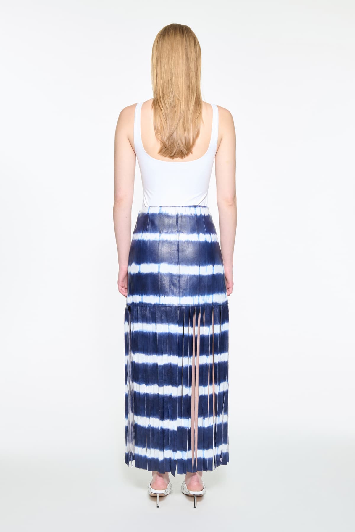 Back view of the Viviana Fringe Skirt in Ocean Tie Dye, is made from leather and features a clean, contemporary silhouette with raw edge fringes. The color is a dark blue with white tie-dye pattern.