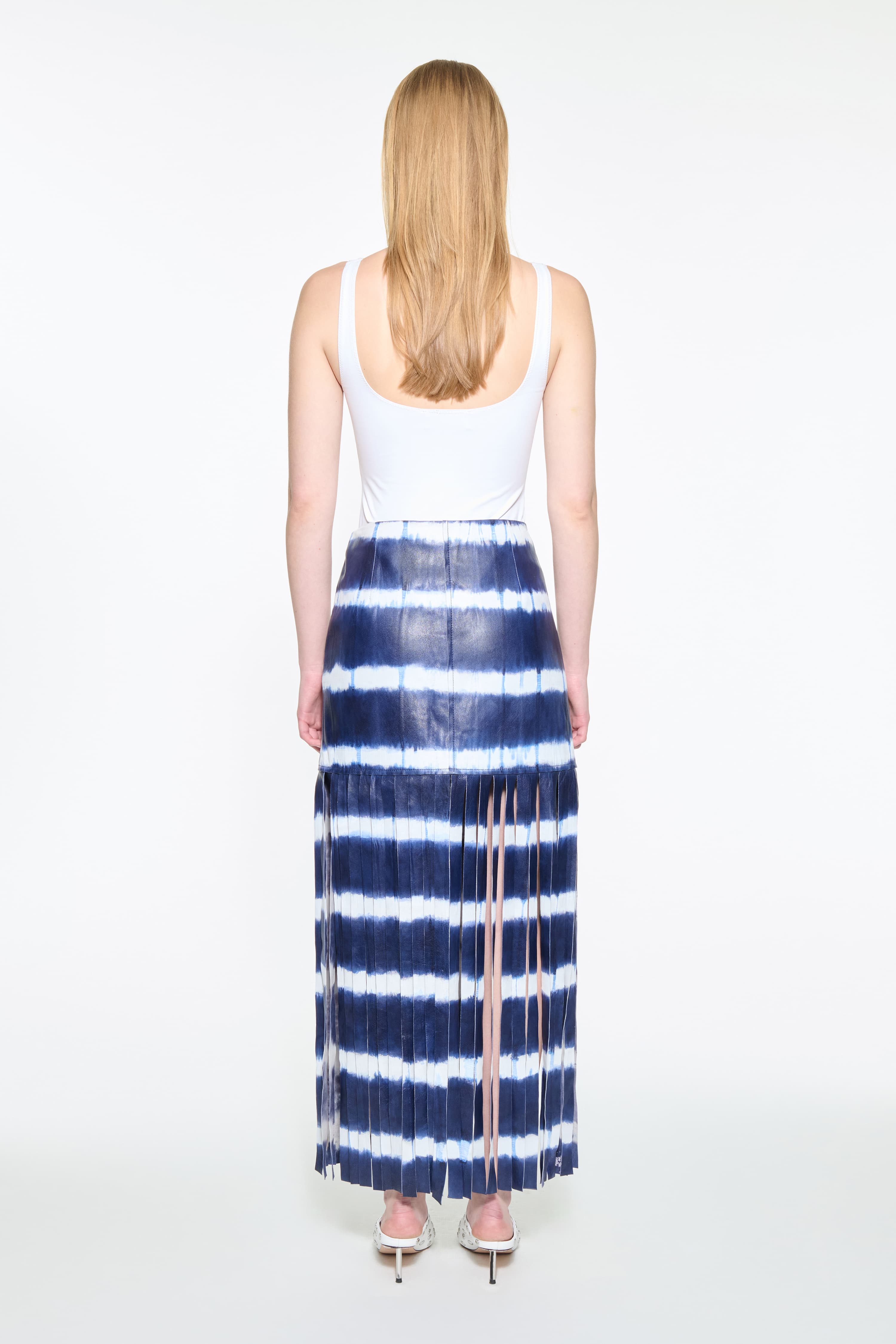 Back view of the Viviana Fringe Skirt in Ocean Tie Dye, is made from leather and features a clean, contemporary silhouette with raw edge fringes. The color is a dark blue with white tie-dye pattern.