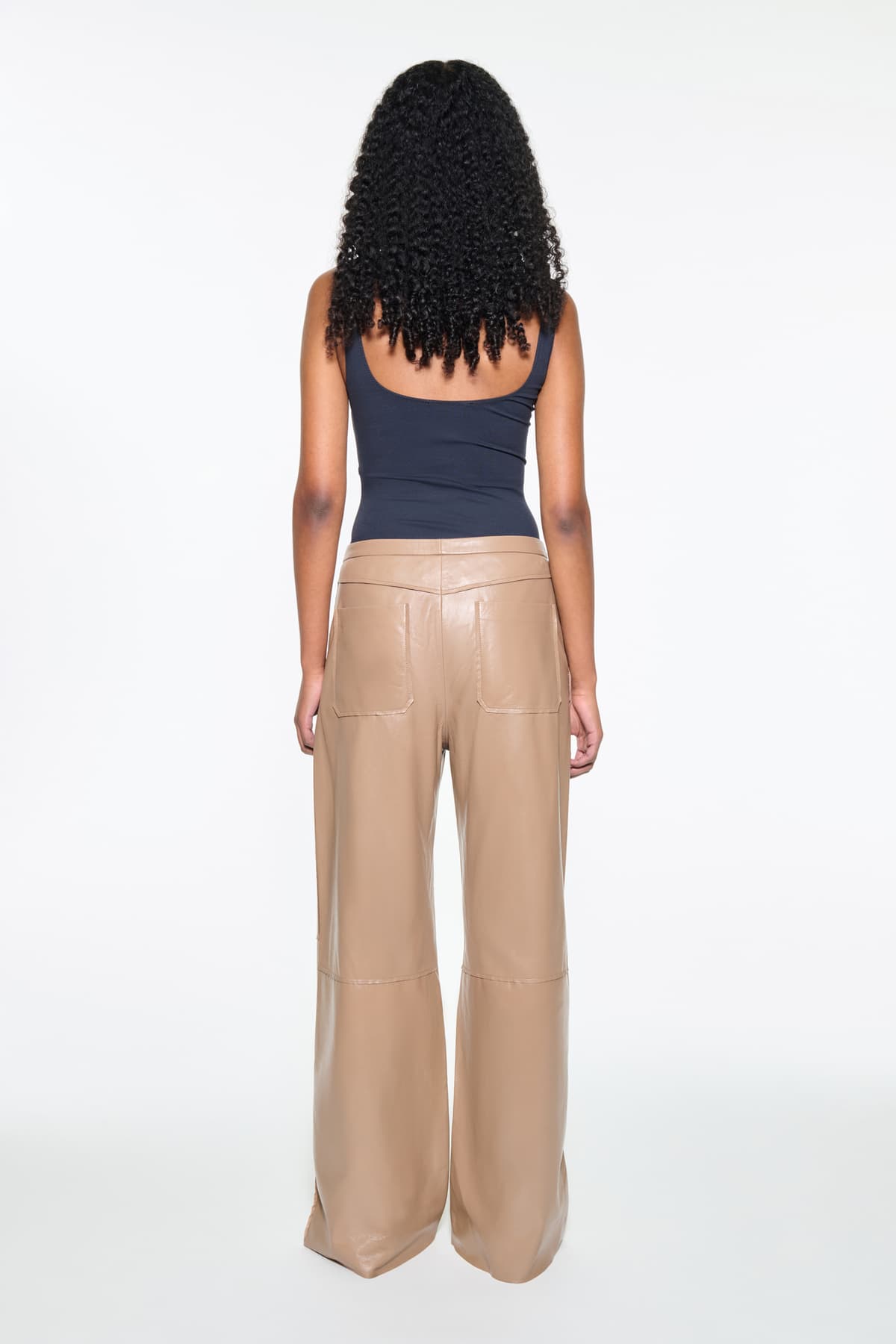 Back view of the Rowyn Trousers in Coconut Brown, are crafted in leather and are designed for a wide silhouette. The color is a light brown shade.