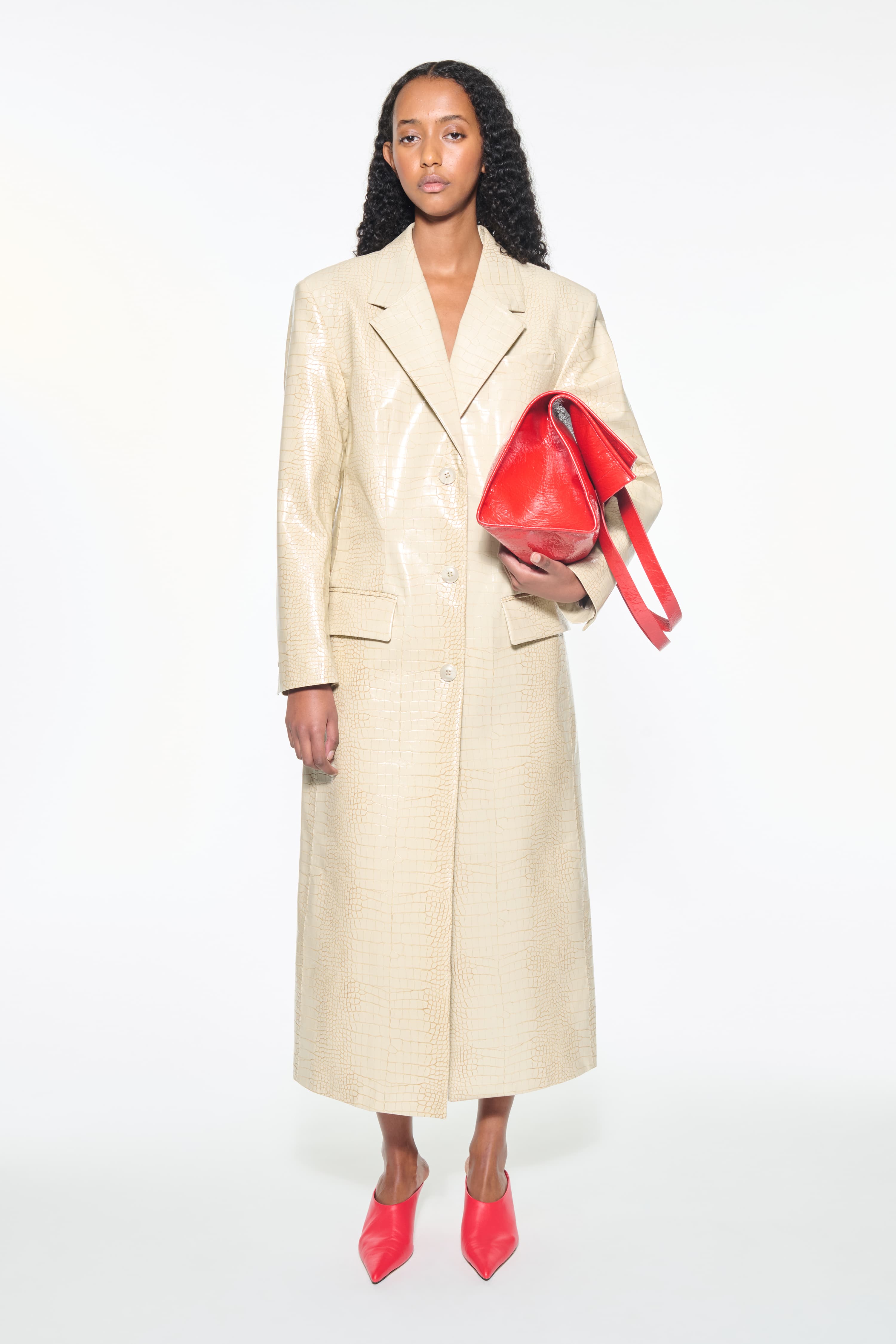 Front view of the Nicki Coat in Seashell, is a faux leather trench coat with a shiny croco pattern. The color is a creamy white tone.