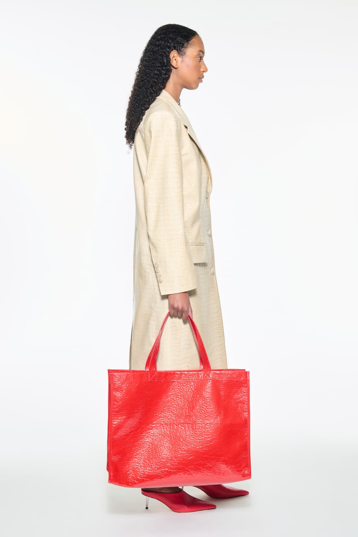 Side view of the Nicki Coat in Seashell, is a faux leather trench coat with a shiny croco pattern. The color is a creamy white tone.