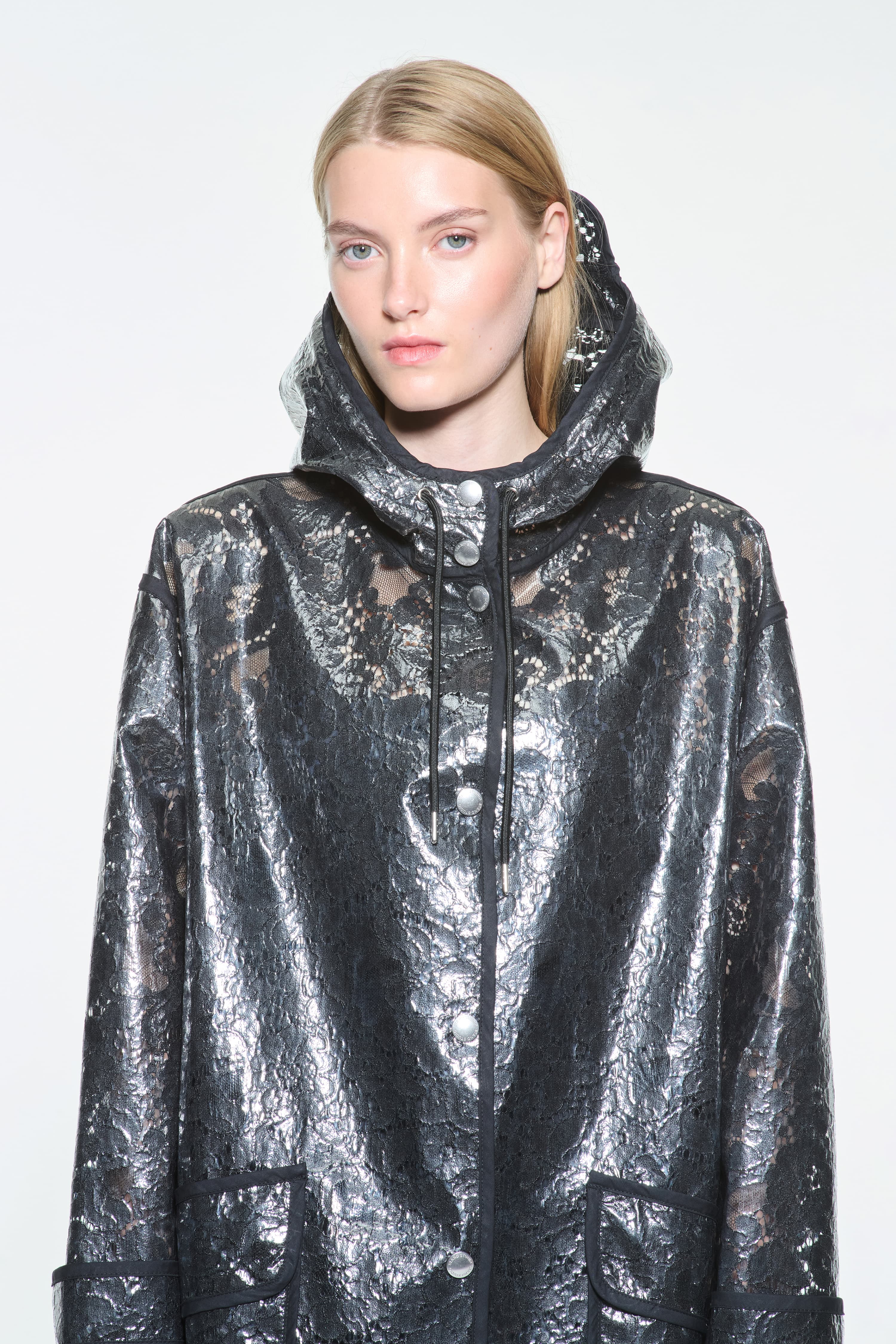 Close-up view of the True Raincoat in Black, is a lightweight raincoat with a lace-patterned design.