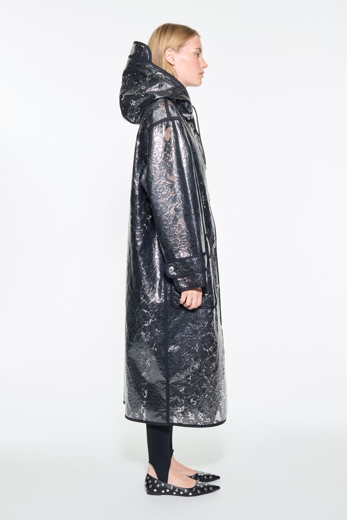 Side view of the True Raincoat in Black, is a lightweight raincoat with a lace-patterned design.
