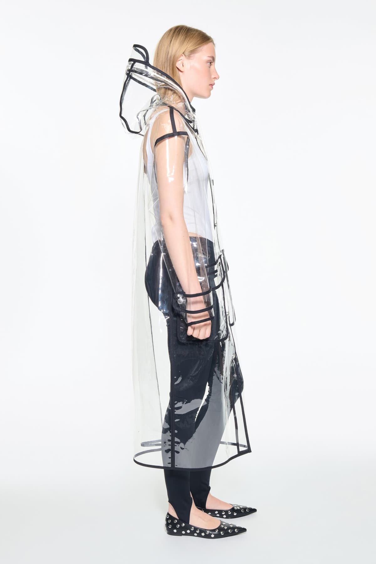 Side view of the True Raincoat in Transparent, is a lightweight, fully transparent raincoat with contrast binding details.