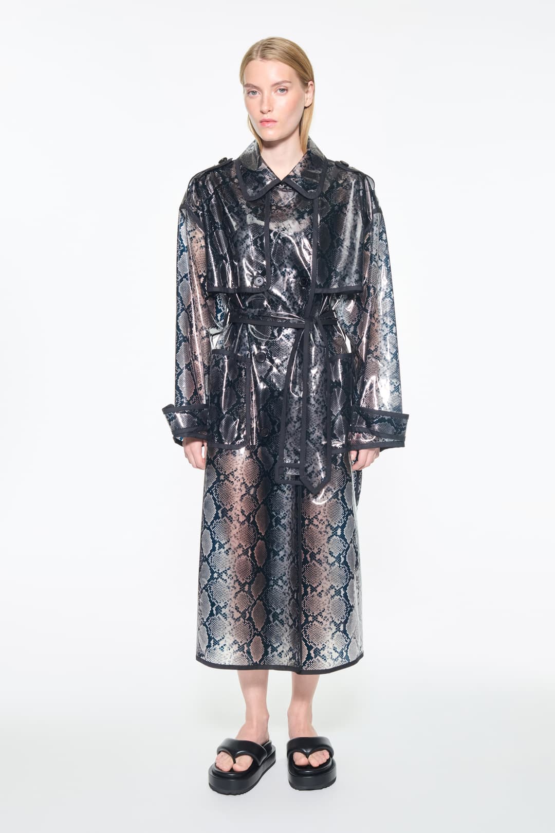 Front view of the Promise Raincoat in Black, is a lightweight raincoat with a glossy snake-patterned finish.