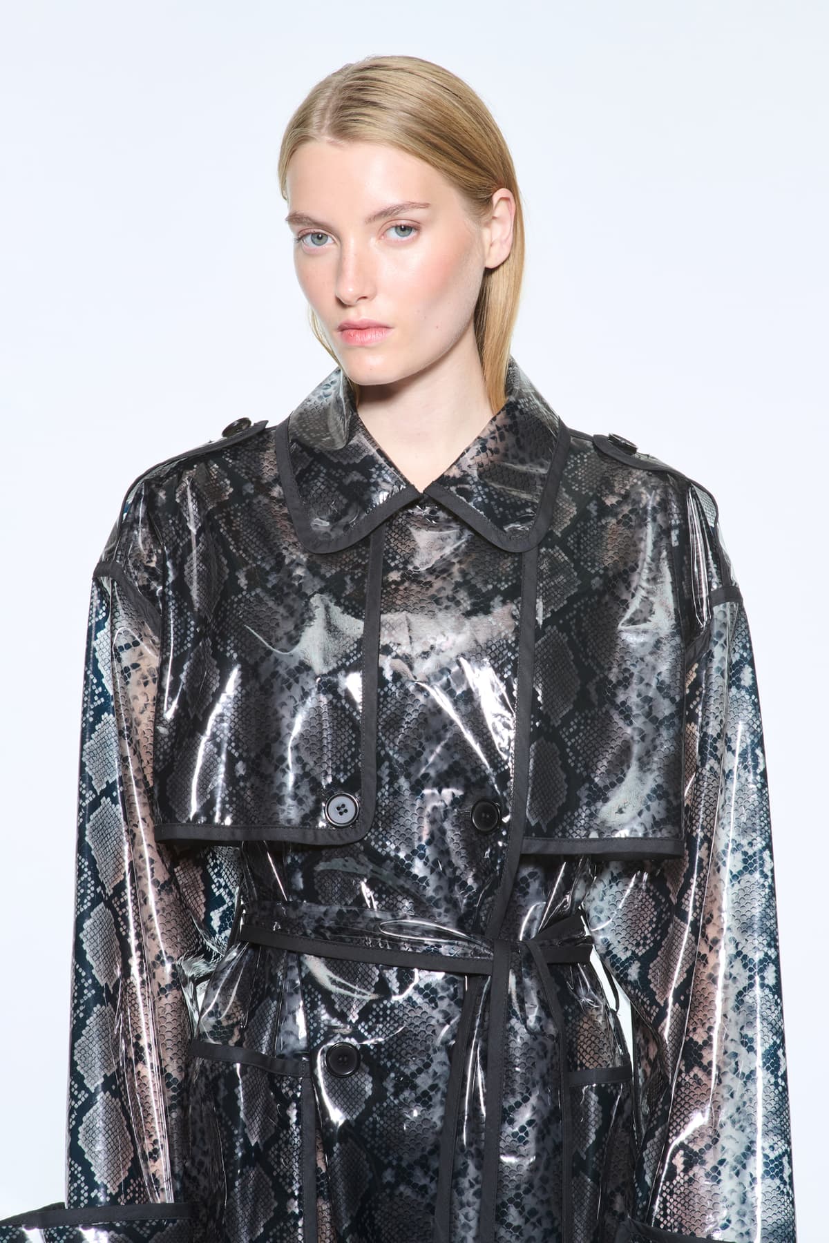 Close-up view of the Promise Raincoat in Black, is a lightweight raincoat with a glossy snake-patterned finish.