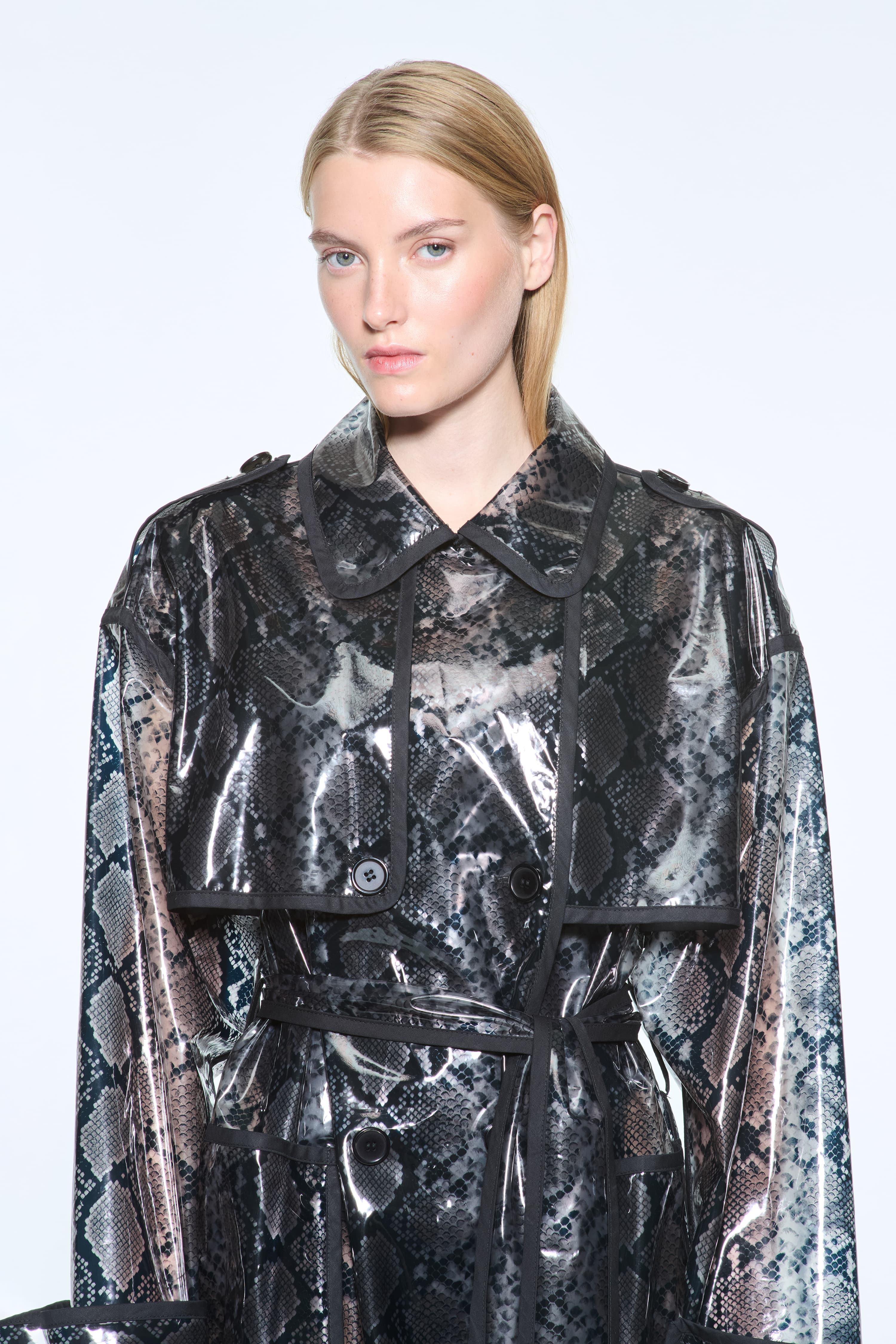 Close-up view of the Promise Raincoat in Black, is a lightweight raincoat with a glossy snake-patterned finish.