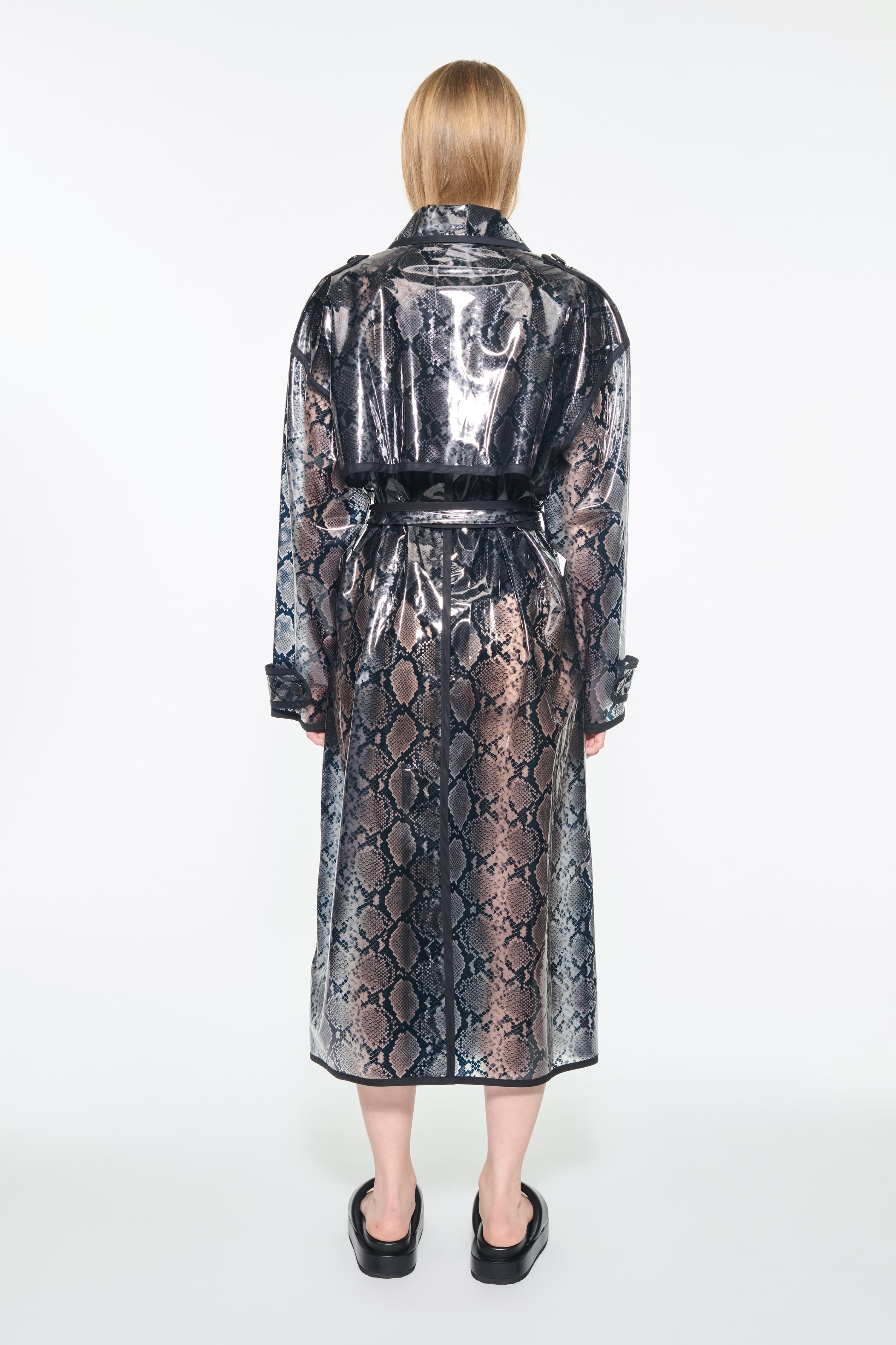 Back view of the Promise Raincoat in Black, is a lightweight raincoat with a glossy snake-patterned finish.